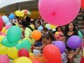Foto da inauguração mostra crianças sorrindo brincando com bexigas coloridas
