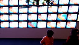 Crianças em frente a diversas telas de televisão