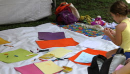 Pano branco com diversos papéis coloridos em cima, e uma criança desenhando.