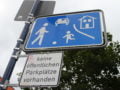 Foto mostra placa de transito na Alemanha com o desenho de adulto e criança jogando bola, um carro e uma casa