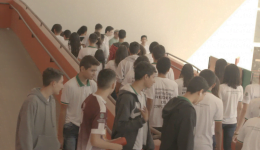 Na foto, jovens caminham e sobem as escadas de uma escola.