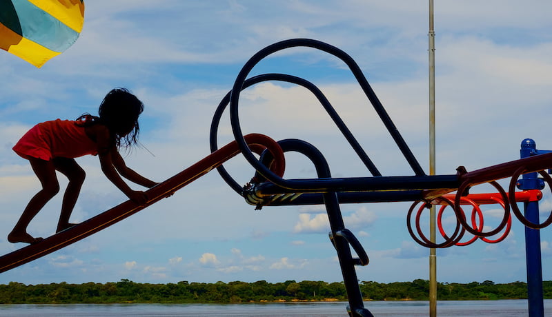 Foto mostra criança subindo em escorregador às margens do rio Araguaiancam em playgrond.