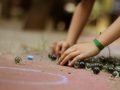 Mãos de uma criança brincando com um monte de bolinhas de gude