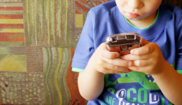 Foto criança mexendo no celular, representando a necessidade de proteção das crianças no ambiente digital