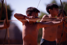 Foto mostra criança indígena segurando um arco e flecha. A foto é do filme Waapa, obra essencial para uma sociedade antirracista