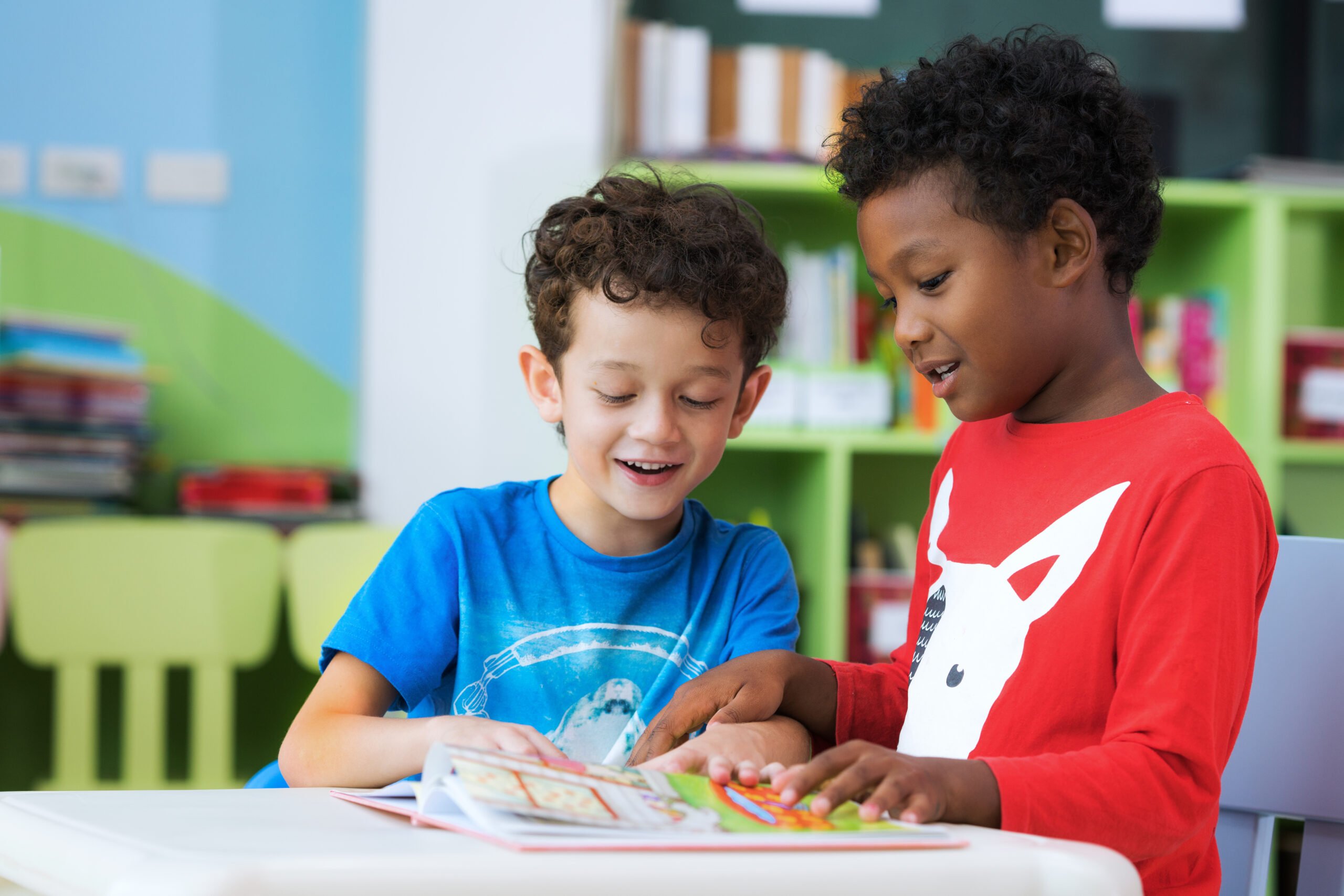 Foto mostra duas crianças, uma preta e outra branca, lendo um livro na escola
