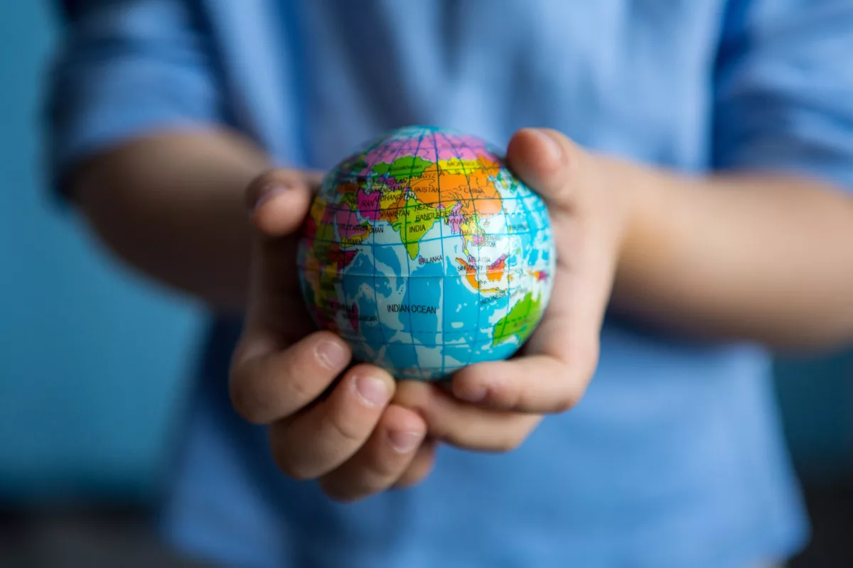 Criança segura uma pequena esfera que remete ao Planeta Terra, em referência à emergência climática