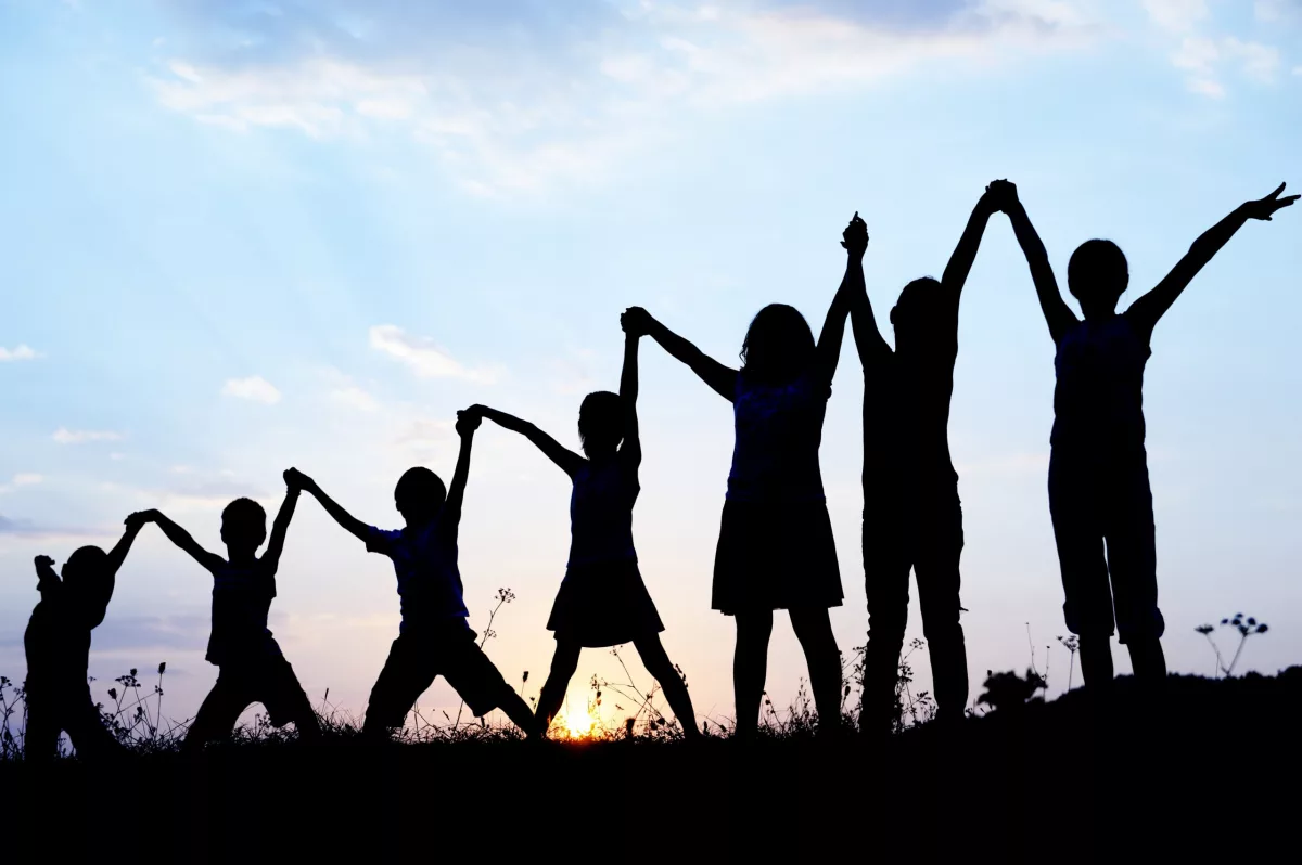 Governo de transição: silhueta de crianças celebrando com as mãos pra cima. Ao fundo, o céu no fim de tarde.