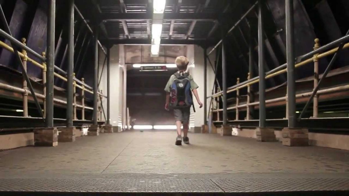 O menino que não queria nascer: na imagem, uma criança pequena caminha em um corredor de concreto.