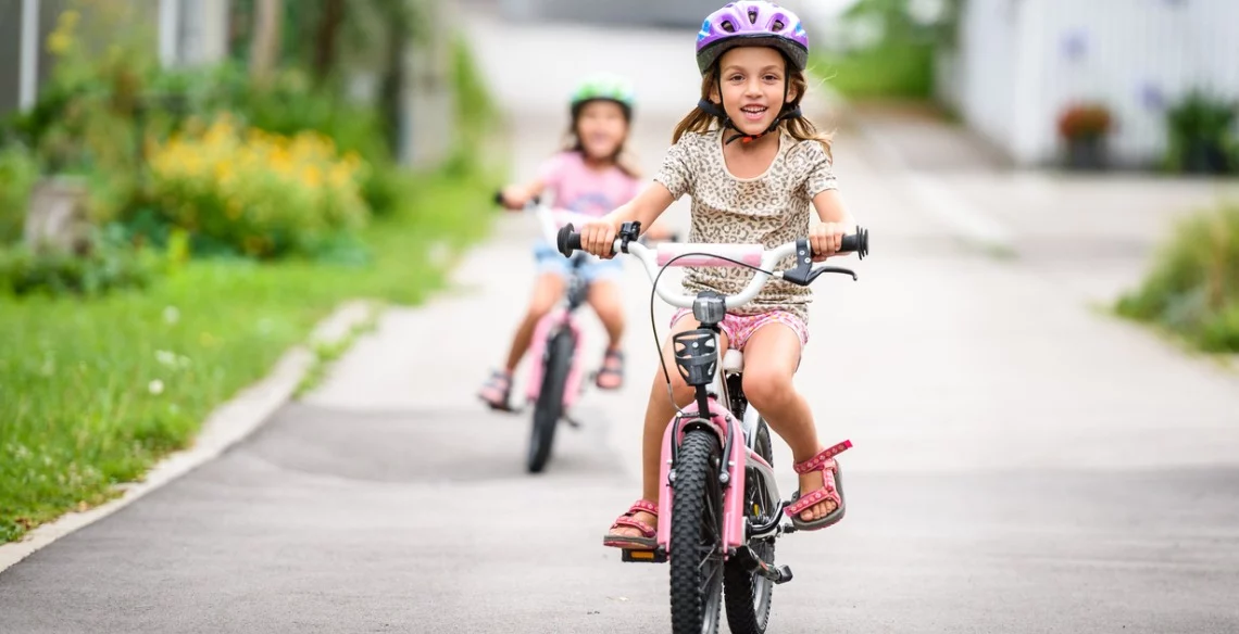 Bicicleta para uma infância saudável: na imagem, duas crianças brancas brincam de bicicleta.