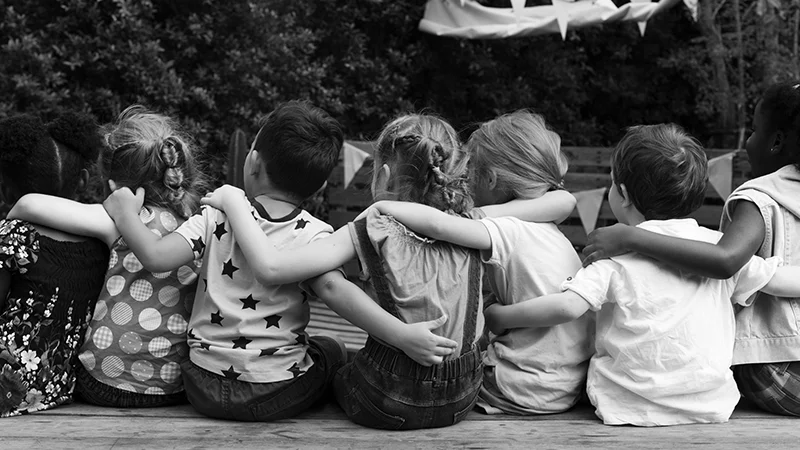 Política de Vulneráveis Simplificada. Imagem em preto e branco de crianças abraçadas de costas.