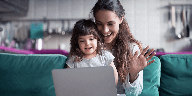 Sugestões para famílias em quarentena: na imagem, uma mulher e uma criança brancas fazem uma vídeochamada e sorriem para a tela do computador.