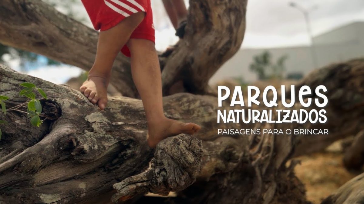 Texto: Parques Naturalizados: paisagens para o brincar. Ao fundo, os pés de uma criança pisando em um grande tronco tombado no chão.