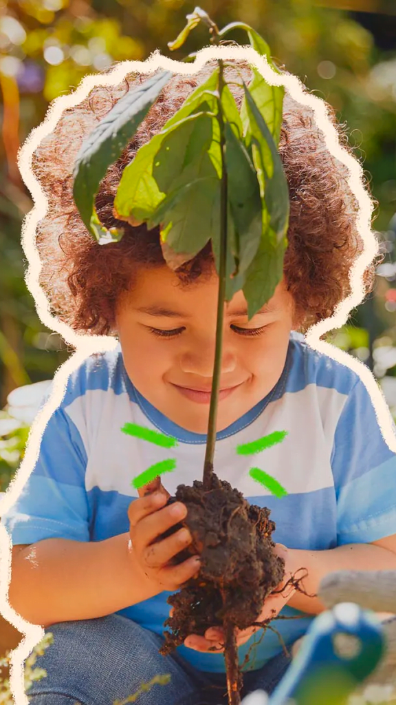 Na imagem, uma criança negra segura a muda de uma árvore.