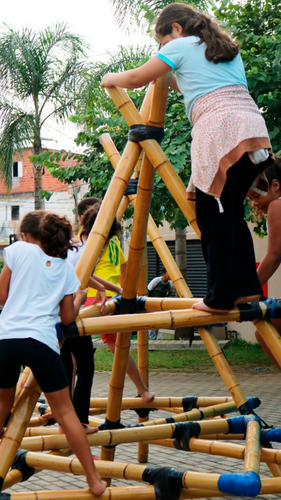 Na imagem, crianças brincam com um brinquedo feito de bambu.