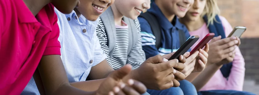 Direitos das crianças em relação ao ambiente digital. Na imagem, crianças estão olhando para telas de celulares.