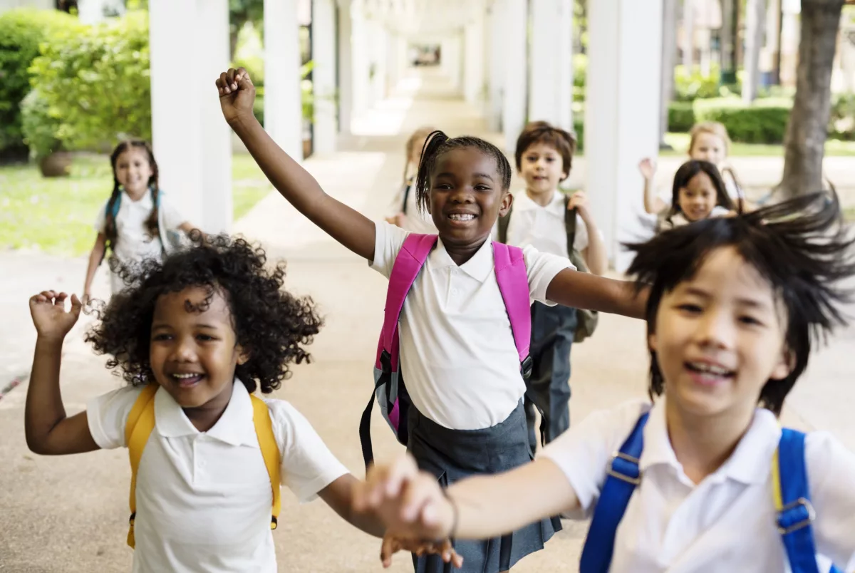 Lei 10.639: na foto, crianças brancas e negras correm em um corredor escolar.