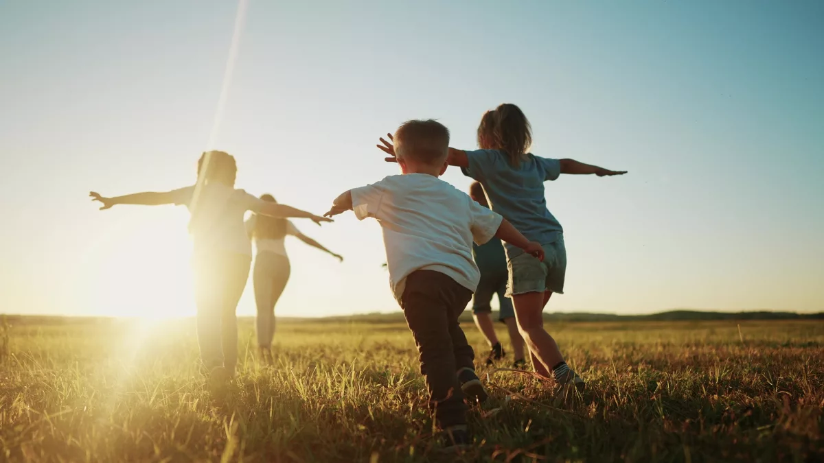 Plano de Ação para as Crianças: na imagem, cinco crianças correm em um gramado ao pôr do sol