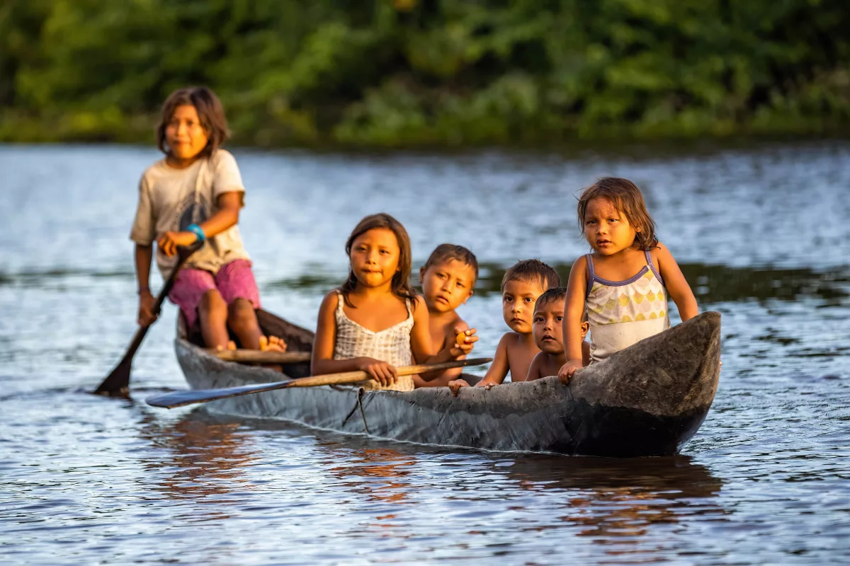crianças indígenas navegam em rio Amazônico numa canoa