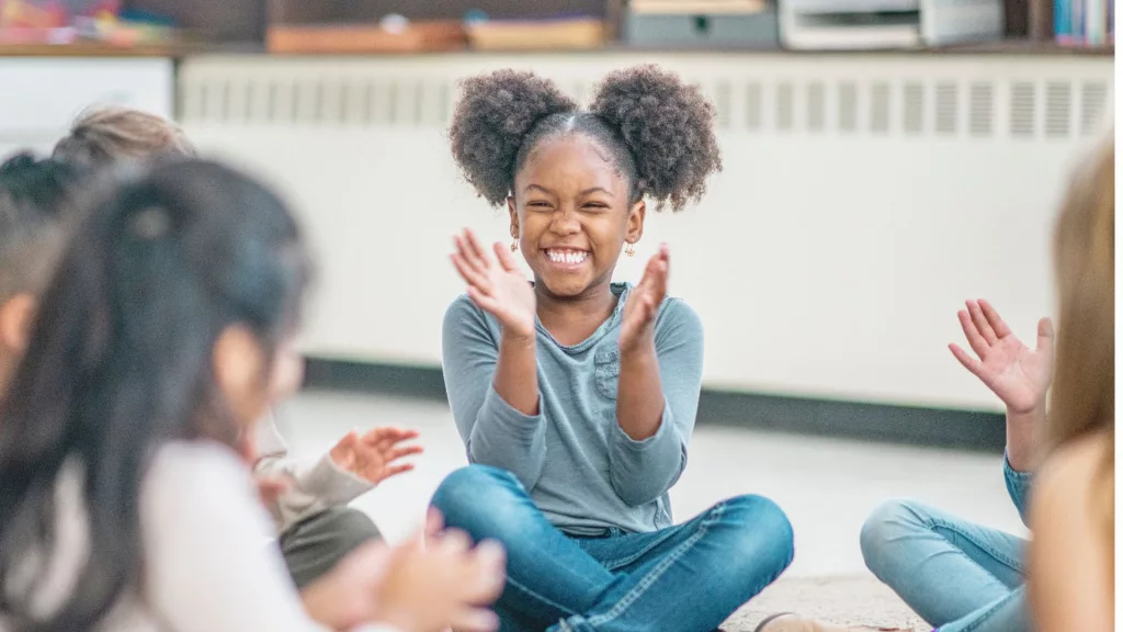 Uma menina negra bate palmas, sorridentes, acompanhada de mais crianças. A imagem ilustra notícia sobre o lançamento de “Ubuntu, eu sou porque nós somos”, uma música para fortalecer a luta antirracista