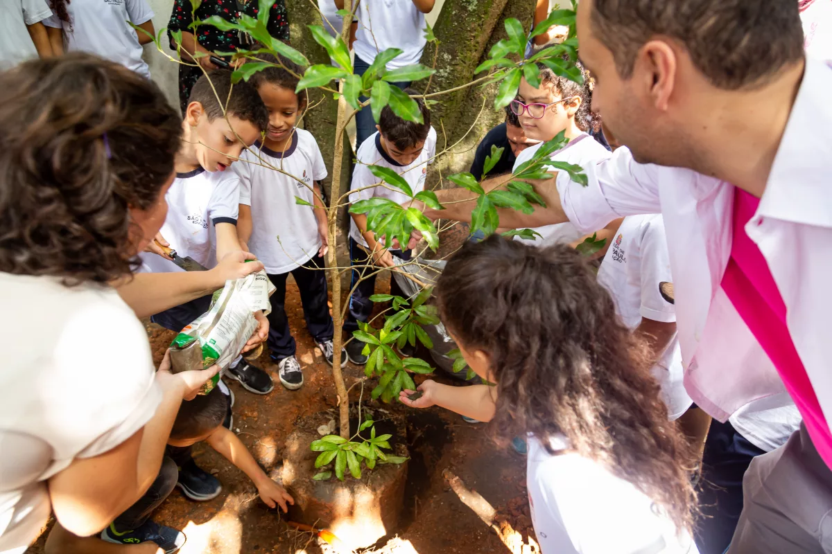 crianças ajudam a plantar árvore na escola Virgílio de Mello Franco
