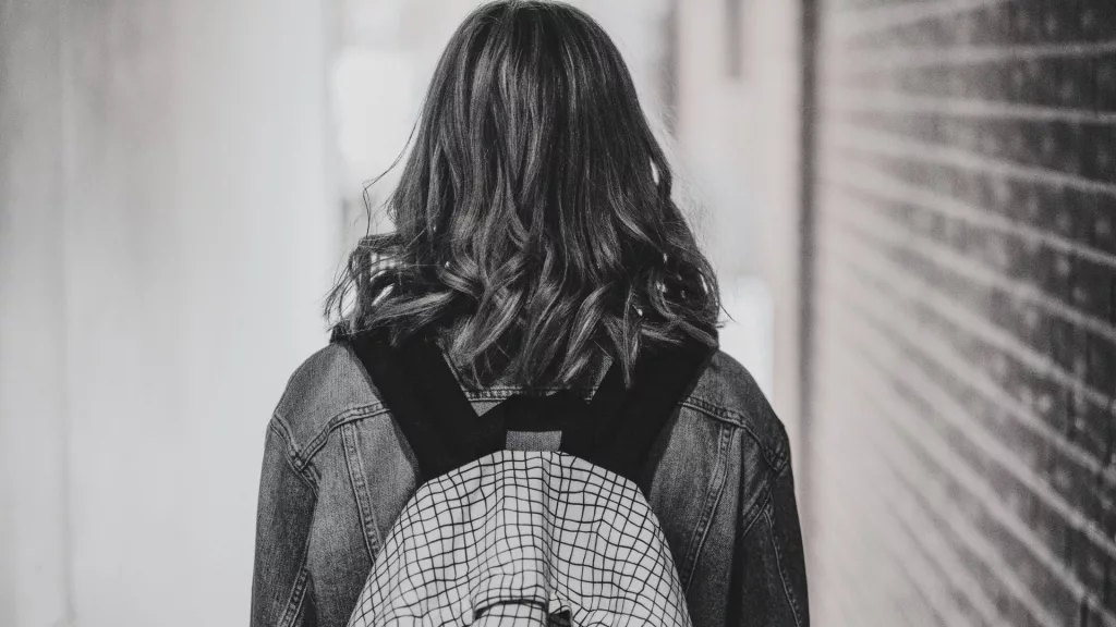Escolas cívico-militares: na imagem em preto e branco, uma estudante aparece de costas, de mochila.