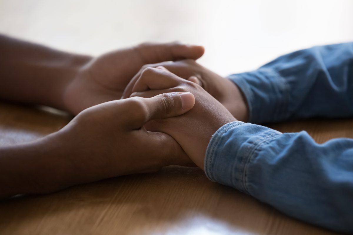 Comentário Geral 27: na foto, as mãos de um adulto seguram as mãos de uma criança