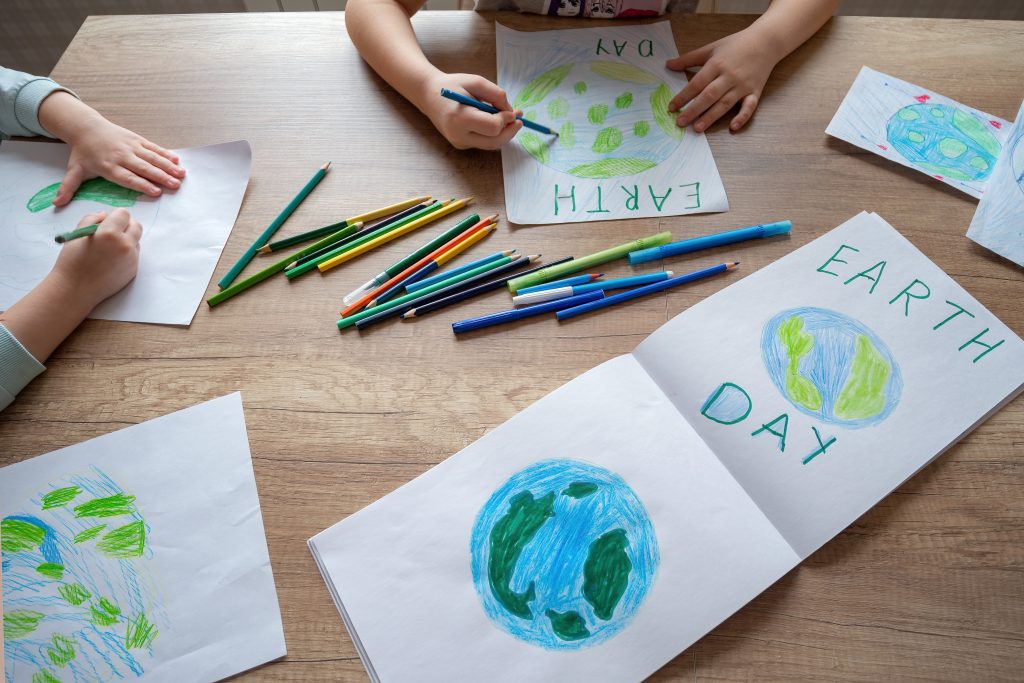 Crianças na COP: na imagem, mãos de crianças desenham o Planeta Terra com lápis coloridos